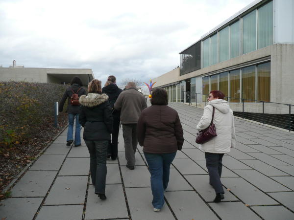 Besucher gehen neben dem Schulgebäude zum Eingang
