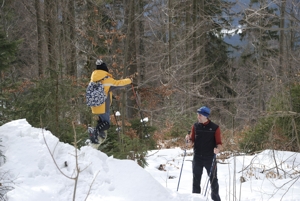 Bild 4: Tom und Patricia lernen vom Schneehügel zu springen. Patricia steht auf dem Hügel, Tom beobachtet das Ganze von unten