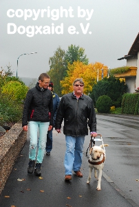 Ausbilderin, Teilnehmer und Hund im zügigen Schritt auf dem Bürgersteig